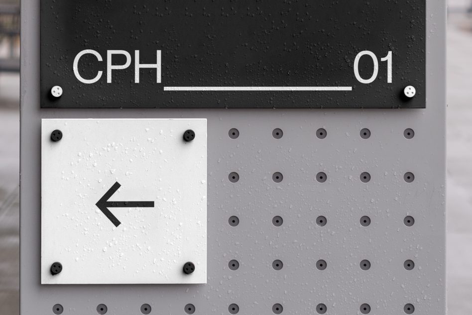 Black directional signage with white arrow on perforated metal building facade